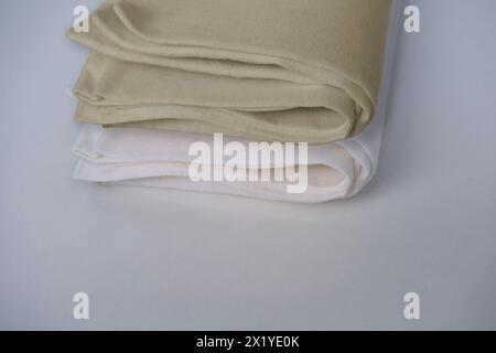 blanc, tissu de lin beige, serviette roulée en plusieurs couches, reposent sur un fond clair, le concept de tissu écologique naturel, colorants naturels Banque D'Images