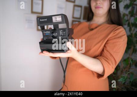 Francfort, Allemagne - mars 2021 : fille tenant un vieux gadget pour la production de photos instantanées dans ses mains, démontrant Polaroid instantcamera de Banque D'Images