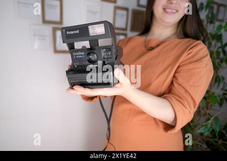 Francfort, Allemagne - mars 2021 : fille tenant un vieux gadget pour la production de photos instantanées dans ses mains, démontrant Polaroid instantcamera de Banque D'Images