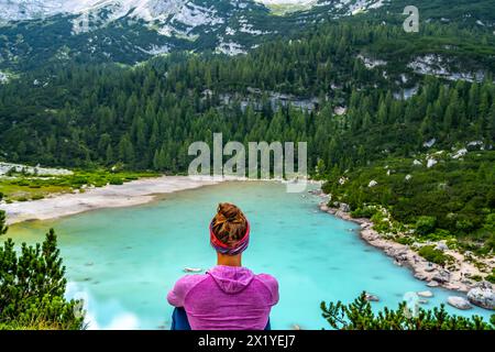 Description : jeune femme sportive jouit d'une vue sur le lac turquoise Sorapis depuis un magnifique point de repos dans l'après-midi. Lac Sorapis, Dolomites, Bell Banque D'Images