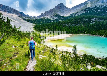 Description : jeune femme sportive marche le long du sentier de randonnée au beau lac turquoise Sorapis dans l'après-midi. Lac Sorapis, Dolomites, Belluno Banque D'Images