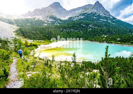 Description : jeune femme sportive marche le long du sentier de randonnée au beau lac turquoise Sorapis dans l'après-midi. Lac Sorapis, Dolomites, Belluno Banque D'Images