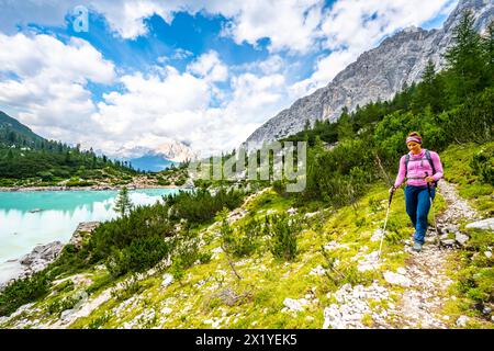 Description : jeune femme sportive marche le long du sentier de randonnée au beau lac turquoise Sorapis dans l'après-midi. Lac Sorapis, Dolomites, Belluno Banque D'Images