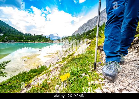 Description : jambes de jeune femme sportive sur le sentier de randonnée au beau lac turquoise Sorapis dans l'après-midi. Lac Sorapis, Dolomites, Belluno, Banque D'Images