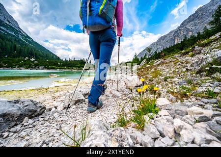 Description : jambes de jeune femme sportive sur le sentier de randonnée au beau lac turquoise Sorapis dans l'après-midi. Lac Sorapis, Dolomites, Belluno, Banque D'Images