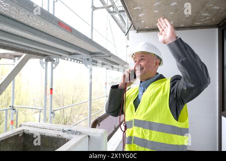 constructeur âgé expérimenté, chef d'équipe de construction, ingénieur de construction dans la protection de casque parlant au téléphone sur le chantier de construction pour le bâtiment re Banque D'Images