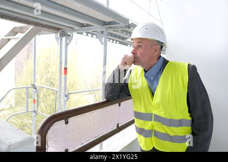 constructeur âgé expérimenté, chef d'équipe de construction, ingénieur de construction dans la protection de casque parlant au téléphone sur le chantier de construction pour le bâtiment re Banque D'Images