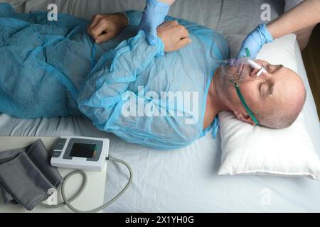 patient homme âgé dans les mensonges de chemise bleue, le médecin met sur le masque à oxygène facial, concept de soins médicaux, anesthésiologie et soins intensifs, oxygène ther Banque D'Images