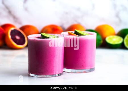 Deux margaritas au sang de noix de coco avec garniture citron vert : paire de cocktails tequila rose pastel servis sur des glaçons dans des verres en pierre Banque D'Images