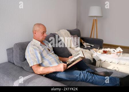 un homme âgé regarde à travers un album avec de vieilles photographies, un concept de souvenirs de jeunesse, d'enfance, de souvenir de sa vie, de ses proches, de sa famille Banque D'Images