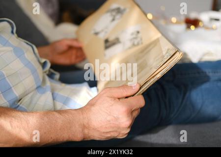 un homme âgé regarde à travers un album avec de vieilles photographies, un concept de souvenirs de jeunesse, d'enfance, de souvenir de sa vie, de ses proches, de sa famille Banque D'Images