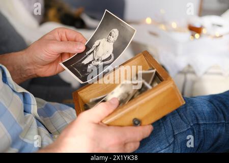 un homme âgé regarde à travers ses vieilles photographies de 1960-1965, le concept de nostalgie et les souvenirs de la jeunesse, de l'enfance, se souvenir de sa vie, relati Banque D'Images