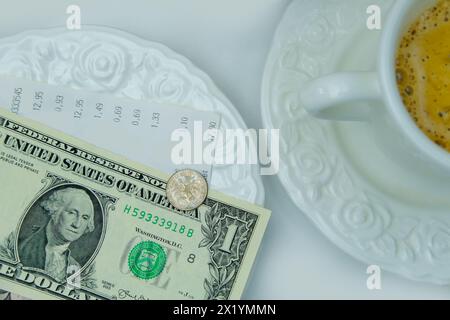 Vue de dessus gros plan sur la plaque blanche avec des billets de dollars américains et des pièces de monnaie, focus sélectif, tasse de café, plats avec de la nourriture, concept de déjeuner dans le restaurant, Banque D'Images