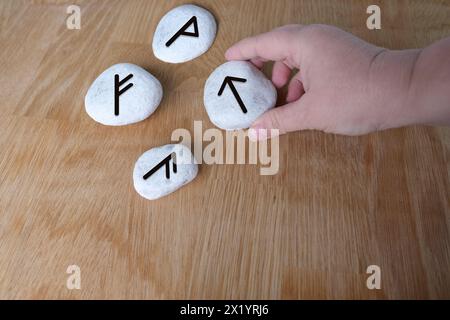 La main de fortuneteller explique la signification des runes scandinaves et slaves sur des pierres plates pour raconter des fortunes pour l'avenir, le concept de magie an Banque D'Images