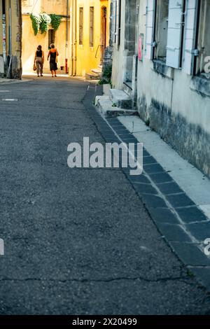 Deux femmes marchant à travers une porte en pierre voûtée dans la ville médiévale d'Arles, France Banque D'Images