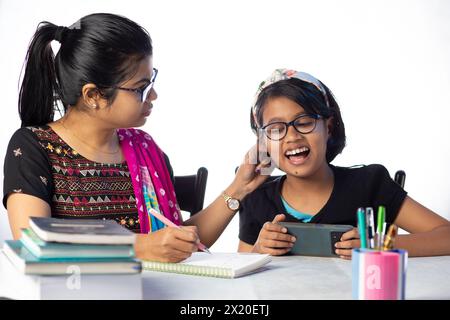 Une étudiante indienne grondée et tirée l'oreille par sa mère enseignante alors qu'elle étudiait pour la dépendance au téléphone intelligent Banque D'Images