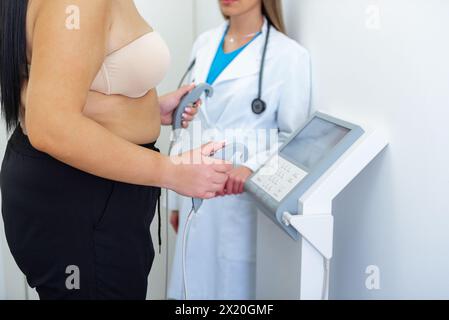 Un praticien de la santé assiste une femme avec un test de composition corporelle à l'aide d'un équipement de pointe. Banque D'Images