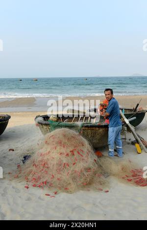 Un pêcheur vietnamien dans son panier coracle bateau à la plage de Cua Dai à Hoi an, Vietnam. Banque D'Images