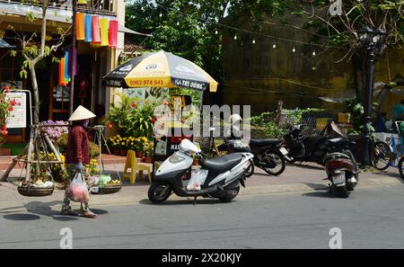 Une femme porte un poteau de transport avec des paniers avec des fruits, également appelé poteau d'épaule, à Hoi an, au Vietnam. Banque D'Images