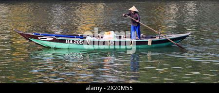 Une vietnamienne ramant transportant des marchandises ou des personnes à travers la rivière Thu bon à Hội an, Vietnam. Banque D'Images