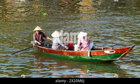 Une vietnamienne ramant transportant des marchandises ou des personnes à travers la rivière Thu bon à Hội an, Vietnam. Banque D'Images