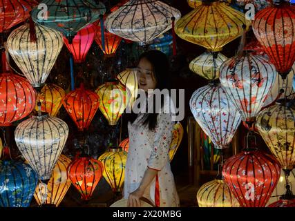 Une femme asiatique posant pour une photo par des lanternes de soie traditionnelles exposées dans un magasin dans la vieille ville de Hội an, au Vietnam. Banque D'Images