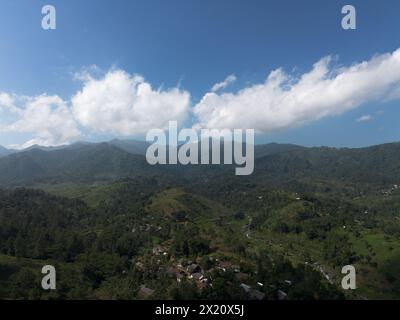 Vue aérienne de collines ondulantes capturées par drone, encadrées par des nuages blancs et un ciel bleu, montrant des crêtes bordées pittoresques Banque D'Images