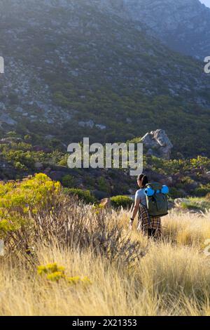 Randonneur féminin biracial marchant à travers les hautes herbes, espace de copie Banque D'Images