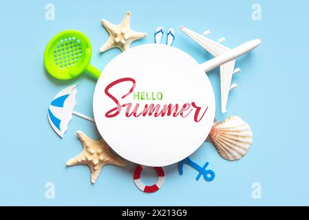 Bonjour Summer. Composition de pose plate avec étoiles de mer, coquillages, accessoires de plage et avion avec blanc rond avec texte Hello Summer sur fond bleu Banque D'Images