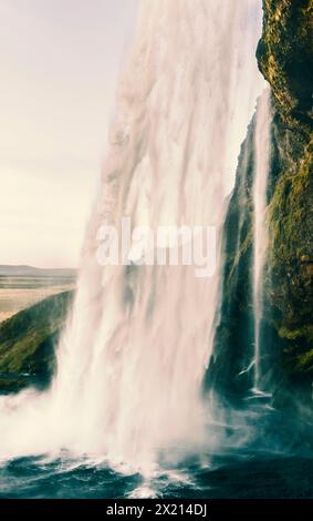 Une cascade est montrée dans l'image, avec une atmosphère brumeuse et sereine. L'eau coule le long d'une falaise rocheuse, créant une scène magnifique et apaisante Banque D'Images