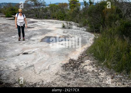 Art rupestre autochtone des premières Nations autochtones dans le parc national de Ku-Ring-Gai Chase, modèle libéré femme voit l'art, Sydney, Nouvelle-Galles du Sud, Australie Banque D'Images