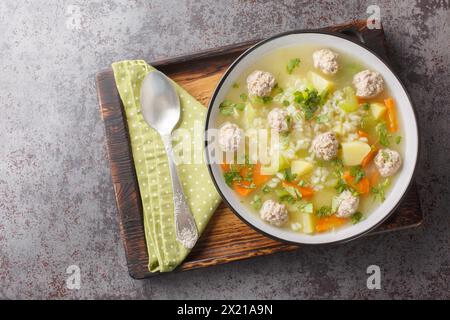 Délicieuse soupe de riz avec boulettes de viande, céleri, carottes, oignons, pommes de terre et herbes gros plan dans un bol sur la table. Vue horizontale de dessus Banque D'Images