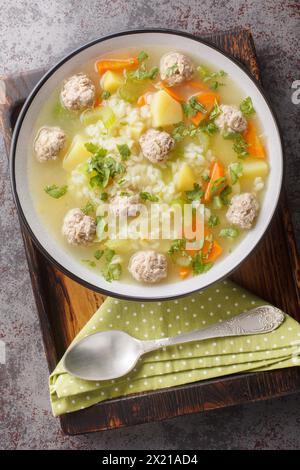 Soupe de riz avec boulettes de viande et légumes gros plan dans un bol sur la table. Vue de dessus verticale Banque D'Images