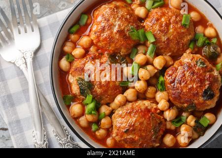 Boulettes de viande frites épicées avec pois chiches, tomate, menthe et oignons verts gros plan dans un bol sur la table. Vue horizontale de dessus Banque D'Images