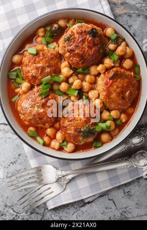 Boulettes d'agneau mijotées avec des pois chiches dans une sauce tomate-menthe gros plan dans un bol sur la table. Vue de dessus verticale Banque D'Images
