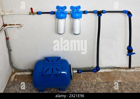 Accumulateur hydraulique, réservoir de stockage par osmose inverse et filtres à cartouche enroulés à chaîne dans le système d'alimentation en eau domestique dans la salle de service. Banque D'Images