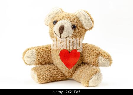 Jouet ours en peluche assis avec un coeur en bois rouge. Banque D'Images