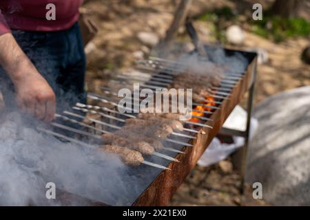 Un homme fait cuire de la viande sur un gril Banque D'Images