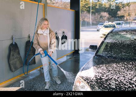 De belles jeunes femmes lavent la voiture au lave-auto en libre-service. Banque D'Images