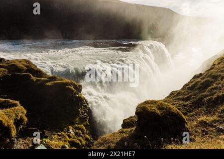 Chute d'eau Gullfoss baignée de soleil en Islande au milieu d'une végétation luxuriante Banque D'Images