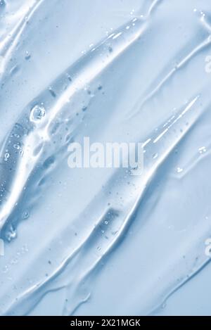 Texture de gel cosmétique transparente sur bleu gros plan. Sérum de visage acide, fond de gel désinfectant. Gel cosmétique transparent avec bulles d'oxygène. Banque D'Images