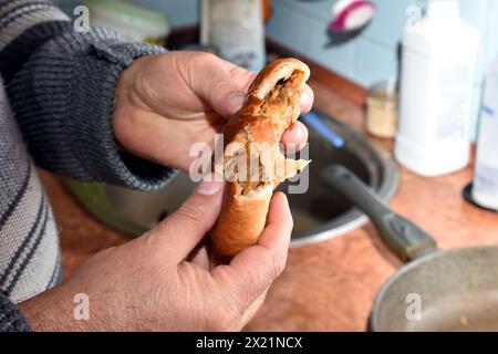 La photo montre les mains d'un homme déchirant un chignon avec la garniture. Banque D'Images