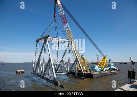 Dundalk (États-Unis d'Amérique). 16 avril 2024. Le Chesapeake, une barge de derrick d'une capacité de levage de 1000 tonnes, soulève une section du pont Francis Scott Key qui bloque le chenal de Fort McHenry, le 16 avril 2024, près de Dundalk, dans le Maryland. Le pont a été heurté par le porte-conteneurs de 984 pieds le 26 mars et s'est effondré tuant six travailleurs. Crédit : MC2 Christine Montgomery/U.S. Navy photo/Alamy Live News Banque D'Images