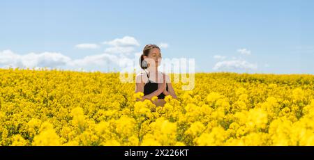 Une femme méditant et profitant du plein air dans un champ de fleurs de canola jaune Banque D'Images