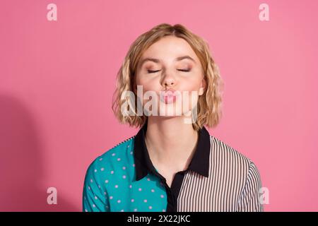 Portrait photo de jolie jeune fille les yeux fermés baiser porter une tenue cyan rayée à la mode isolé sur fond de couleur rose Banque D'Images