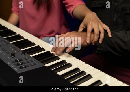 Professeur latino-américain méconnaissable enseigne et corrige la posture pour jouer du clavier de piano. Concept de leçons de musique Banque D'Images