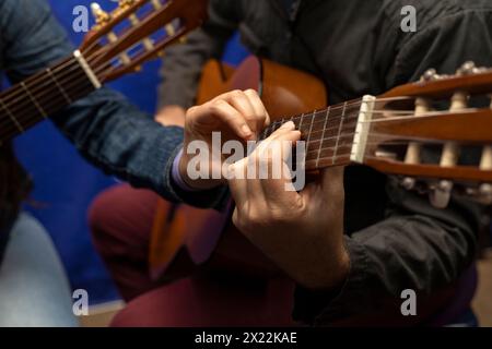 Professeur latino-américain méconnaissable corrige et enseigne les accords à la guitare. Leçons de musique conceptuelle Banque D'Images