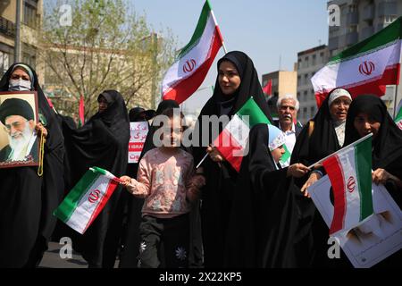 19 avril 2024, Téhéran, Iran : des femmes voilées iraniennes brandissent des drapeaux iraniens lors d'un rassemblement anti-israélien à Téhéran. Les systèmes de défense aérienne au-dessus de la ville centrale d'Ispahan ont détruit trois objets aériens tôt le 19 avril. Les explosions surviennent après une attaque par drone et missile menée par le corps des Gardiens de la révolution islamique (CGRI) contre Israël le 13 avril, à la suite d'une frappe aérienne contre l'ambassade iranienne en Syrie, qui, selon l'Iran, a été menée par Israël. r de la guerre à GazaCredit : Zuma Press/Alamy Live News Banque D'Images