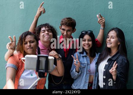 Groupe de jeunes étudiants latino collégiaux en dehors de la classe prendre des photos et passer un bon moment Banque D'Images