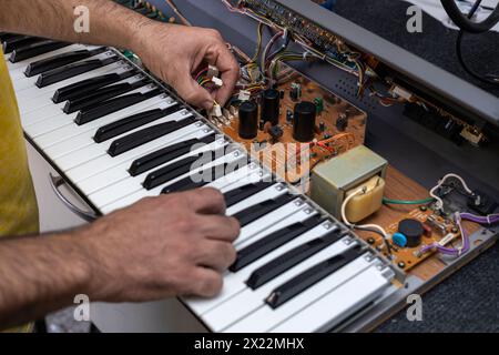 Un technicien en électronique latino-américain répare un piano dans le centre de service. Réparation de concept, musique, électronique Banque D'Images